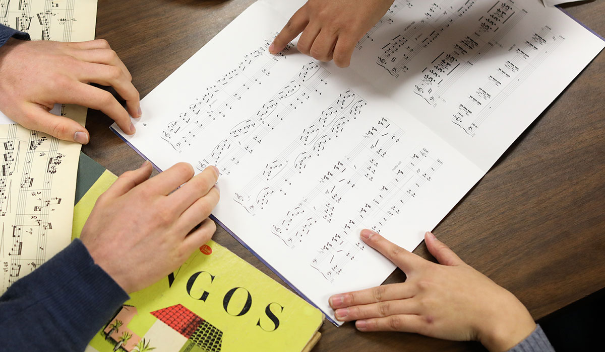 Hands pointing at sheet music on table