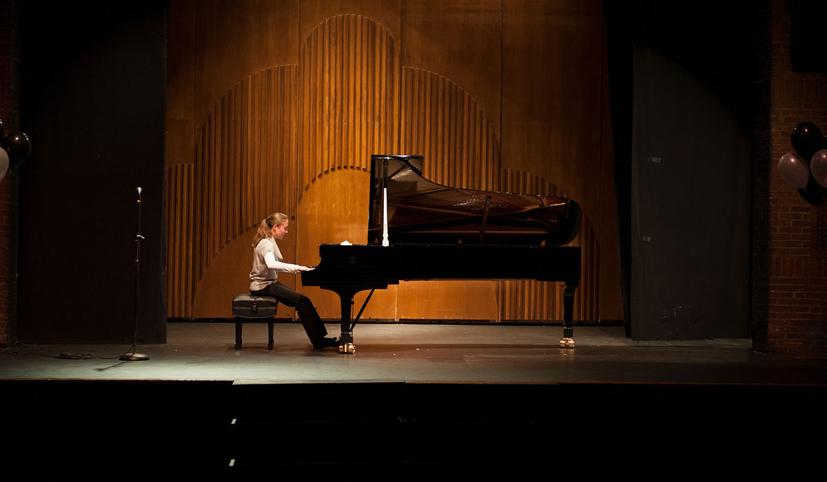 Student playing piano on stage